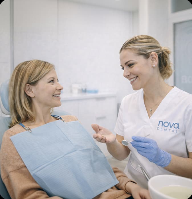 Paciente en un gabinete con una dentista y ambas sonriendo