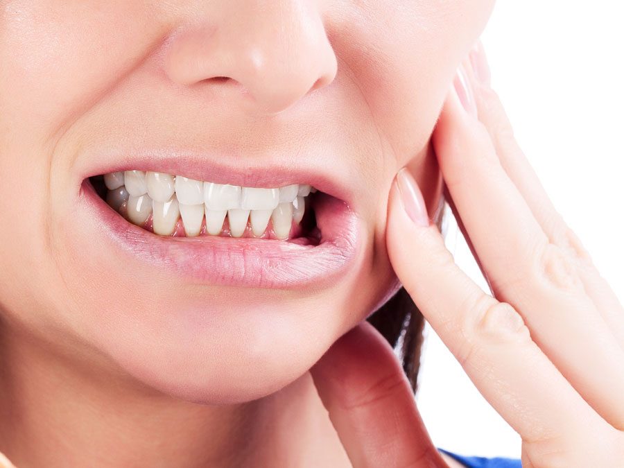 Mujer tocándose la cara tras sufrir dolor por su sensibilidad dental