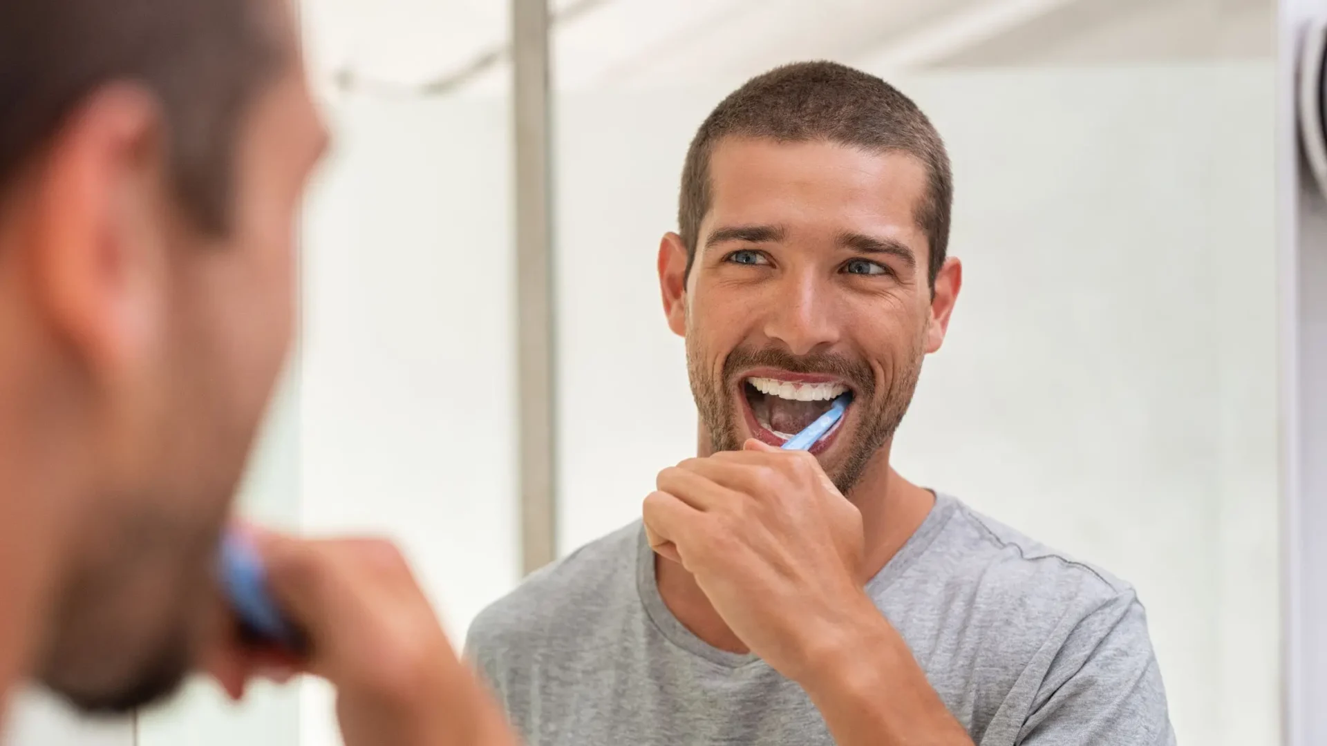 Hombre lavándose los dientes frente a un espejo