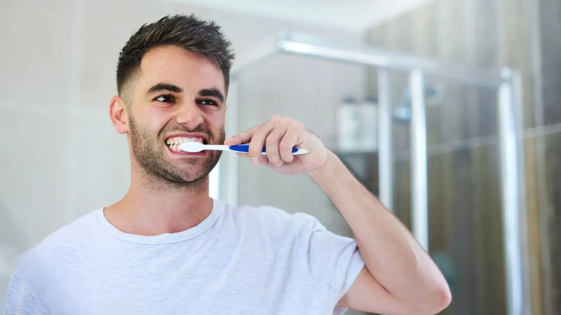 Hombre cepillándose los dientes con insistencia frente al espejo para quitarse bien el sarro dental