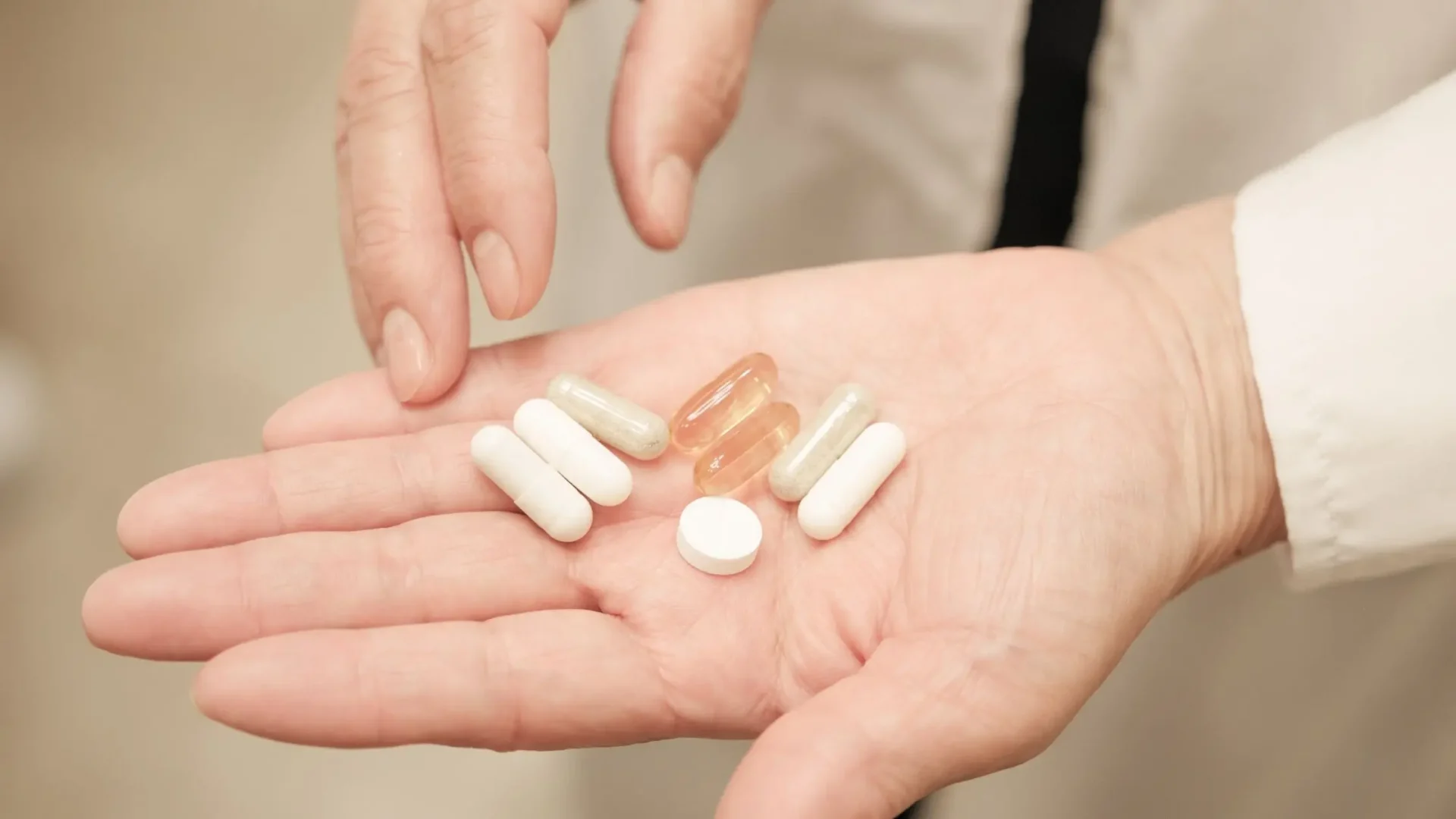 Diferentes pastillas, blancas y transparentes en la mano de una persona